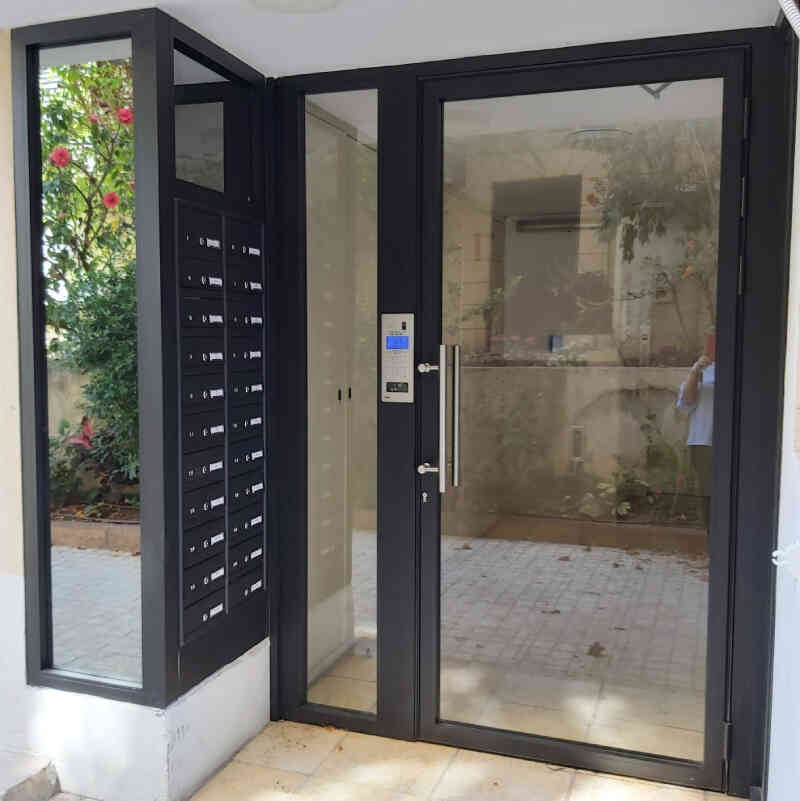דלת כניסה לבניין בעיצוב מיוחד בשילוב אלומיניום וזכוכית