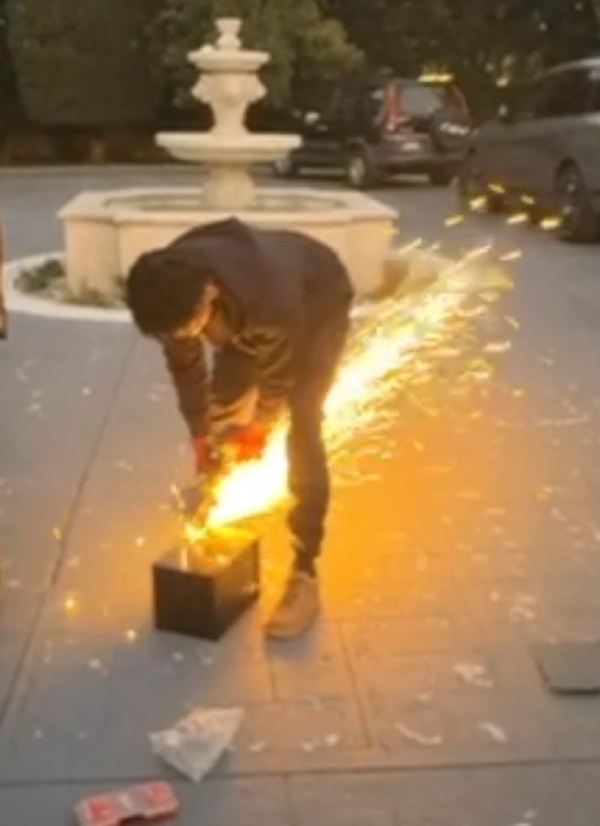 A locksmith working on a safe unlocking job outdoors using specialized tools, with visible sparks.