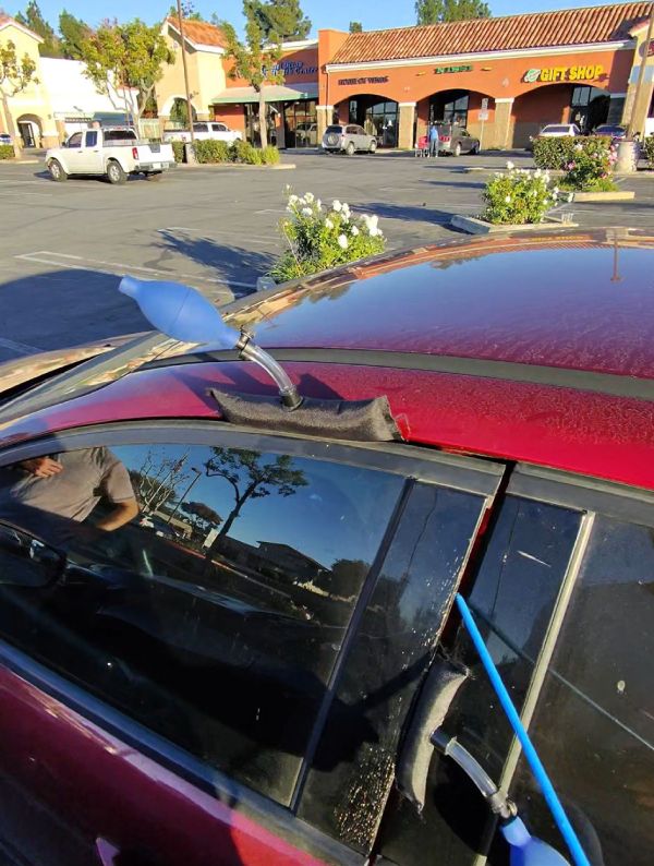 A locksmith opening a car during a vehicle lockout call.