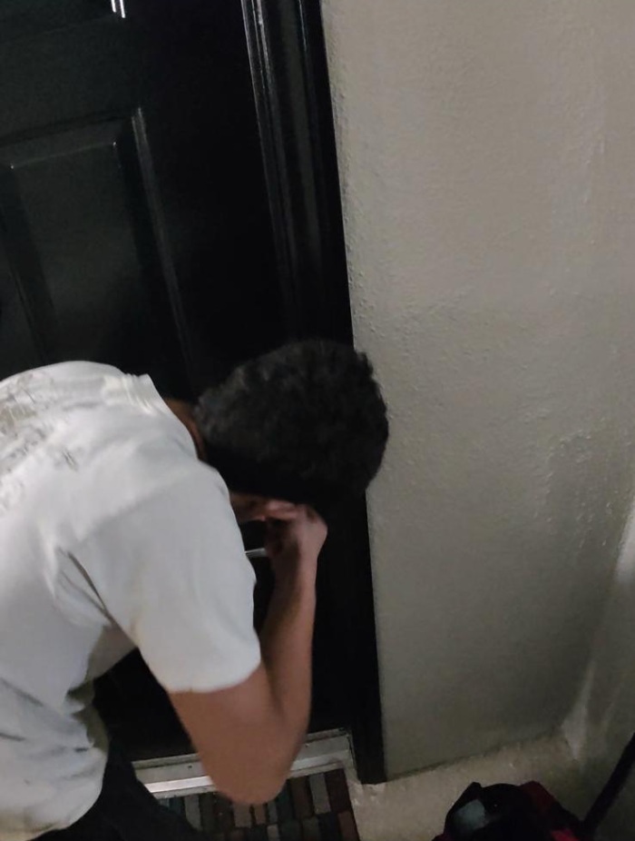 A locksmith working near a door lock to restore entry to a home.