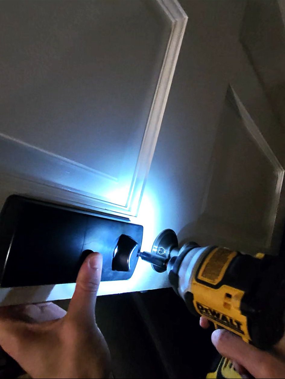 A locksmith working on a residential front door lock using professional tools.